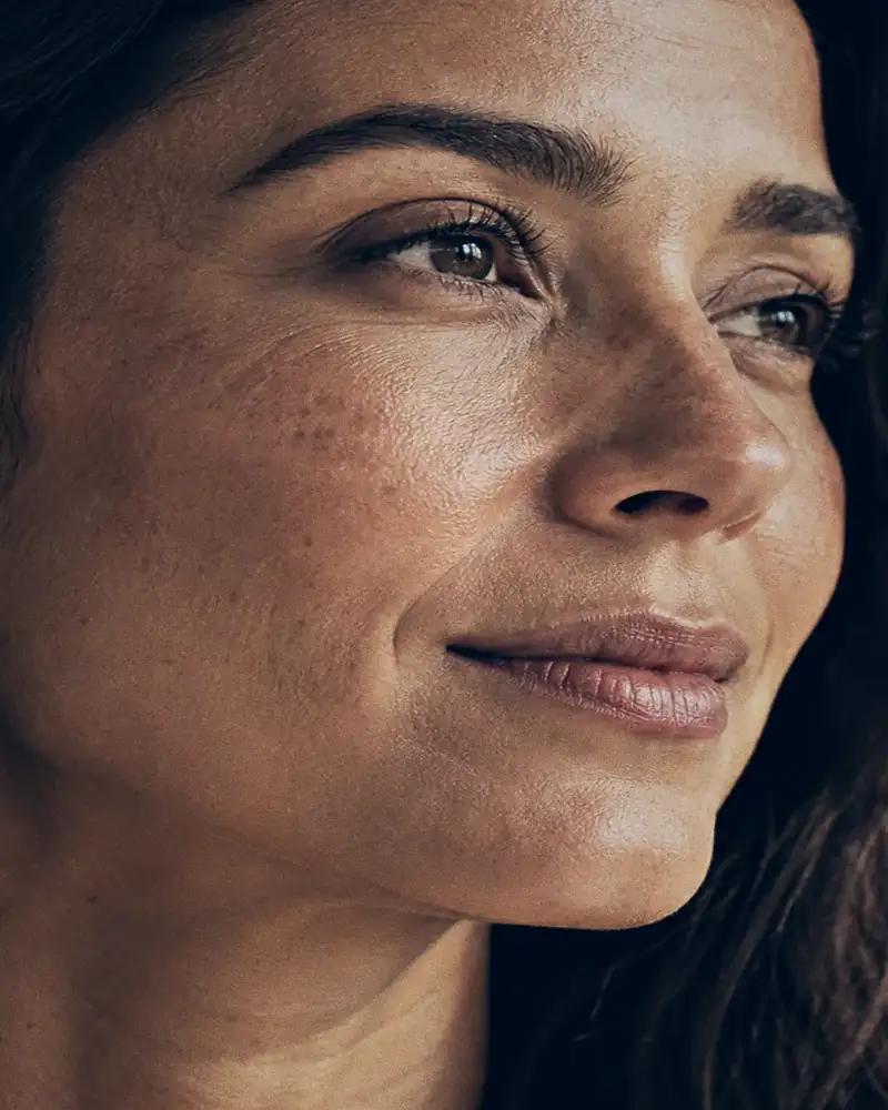 Detalhe do rosto de uma mulher em luz natural, com textura de pele preservada