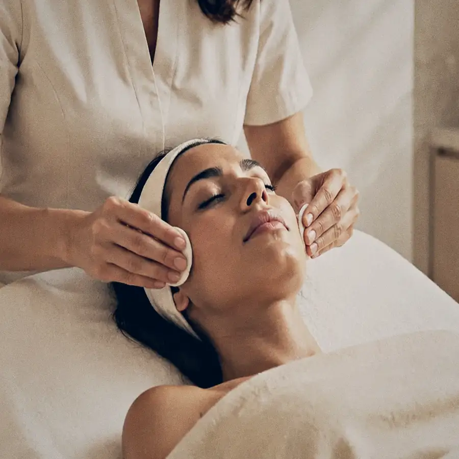 Mãos de profissional da Clínica RK conduzindo um protocolo facial em uma paciente